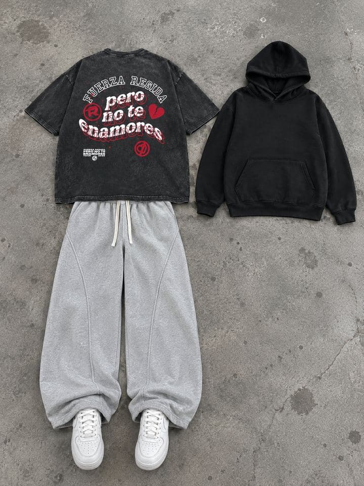 Washed black graphic tee, black hoodie and grey sweatpants laid flat on a concrete floor